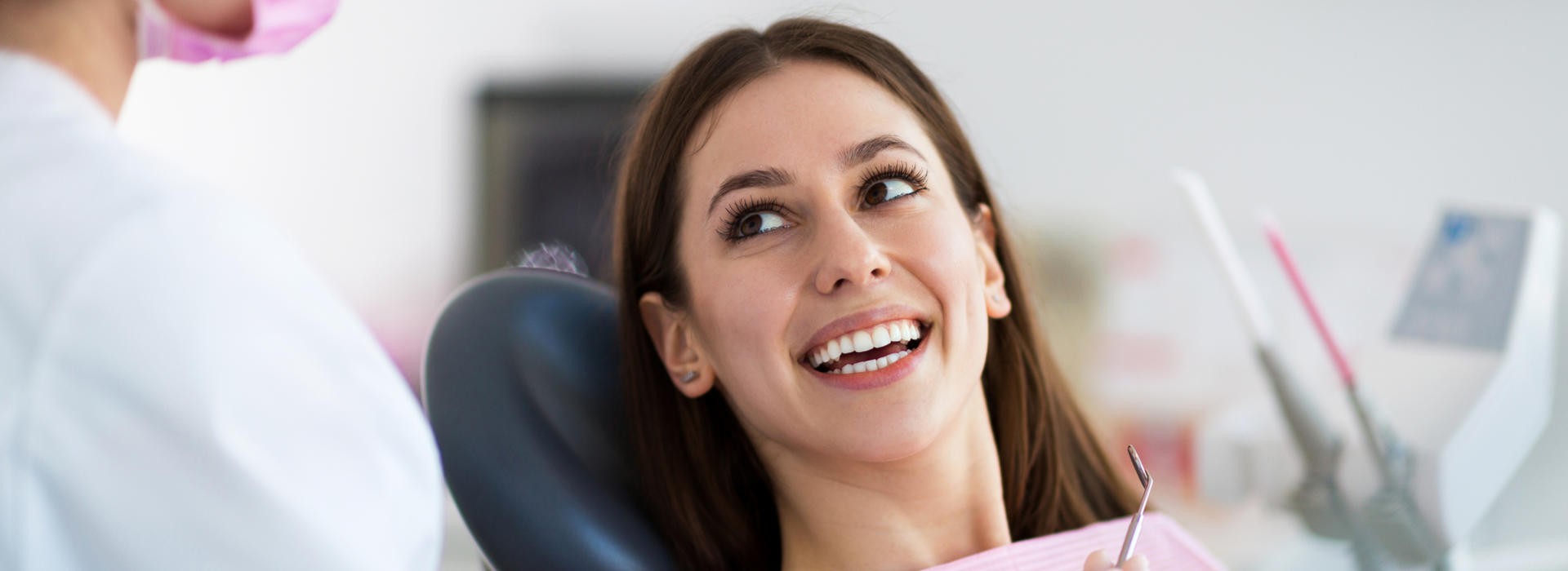A woman is smiling after dental crowns and bridges.